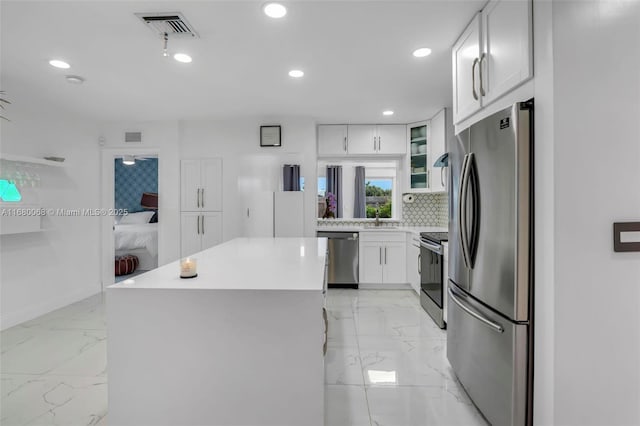 kitchen with sink, a center island, stainless steel appliances, decorative backsplash, and white cabinets