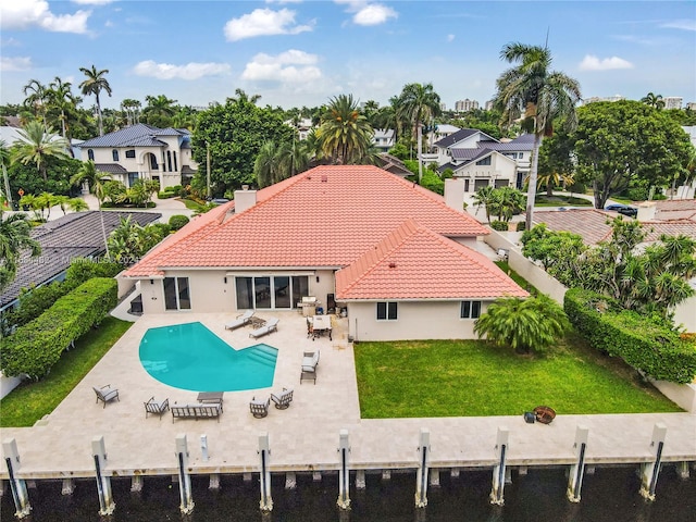 rear view of property with a patio area, a water view, and a lawn