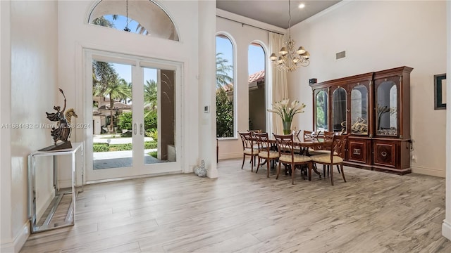 34 Pelican Dr, Fort Lauderdale, FL 33301 - dining room featuring a towering ceiling, wood finished floors, a chandelier, and baseboards