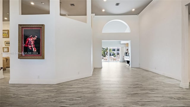 hall featuring ornamental molding, hardwood / wood-style floors, and a high ceiling