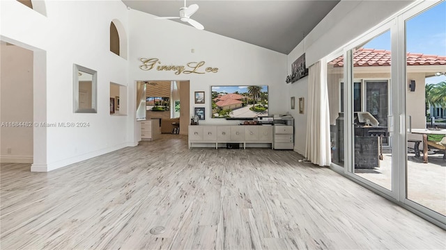 unfurnished living room featuring ceiling fan, high vaulted ceiling, and light wood-type flooring