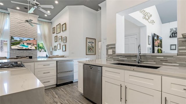 kitchen with white cabinets, tasteful backsplash, ornamental molding, sink, and stainless steel appliances