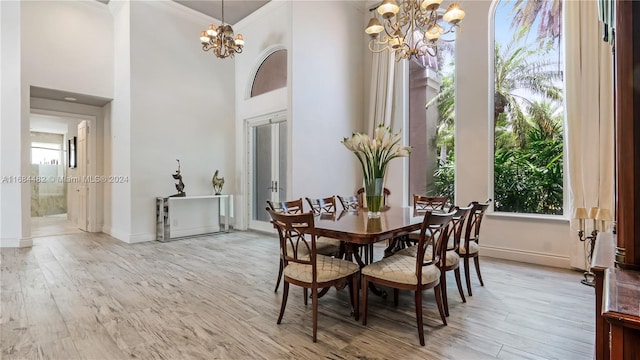 dining space featuring light hardwood / wood-style floors, a towering ceiling, a chandelier, and a wealth of natural light