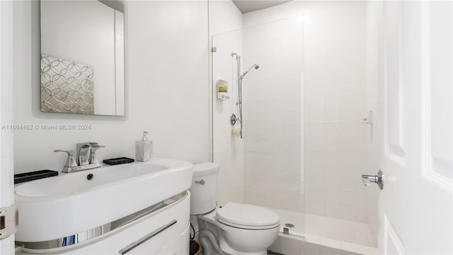 bathroom with toilet, vanity, and a tile shower