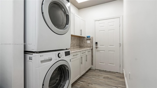 washroom with cabinets, stacked washing maching and dryer, and light hardwood / wood-style floors