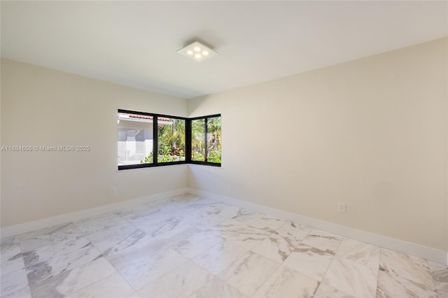 spare room featuring marble finish floor and baseboards