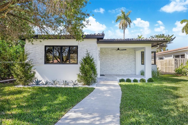 view of front of house featuring ceiling fan, a front yard, fence, and stucco siding