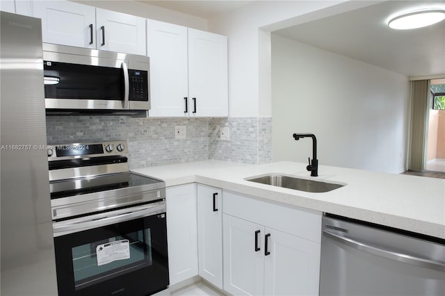 kitchen featuring tasteful backsplash, sink, kitchen peninsula, stainless steel appliances, and white cabinets