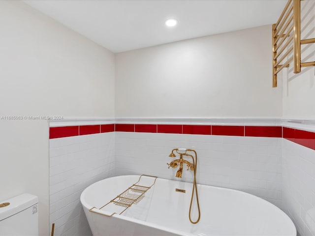 bathroom featuring tile walls, toilet, and a bathing tub