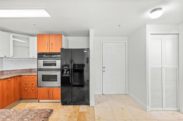 kitchen featuring double oven, black refrigerator with ice dispenser, and light tile patterned flooring