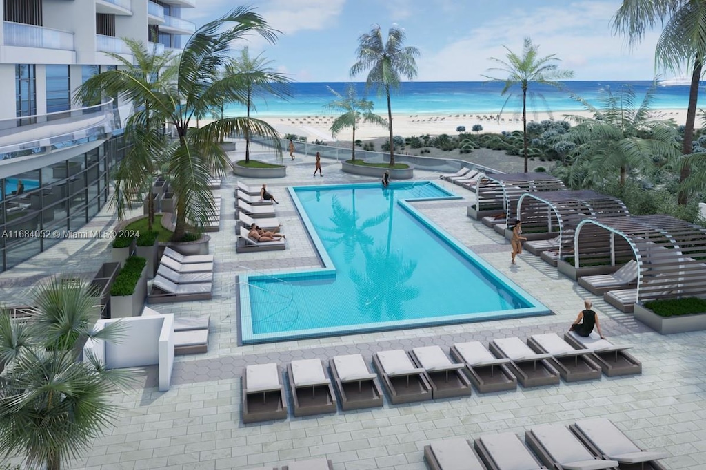 view of swimming pool with a view of the beach, a patio, and a water view