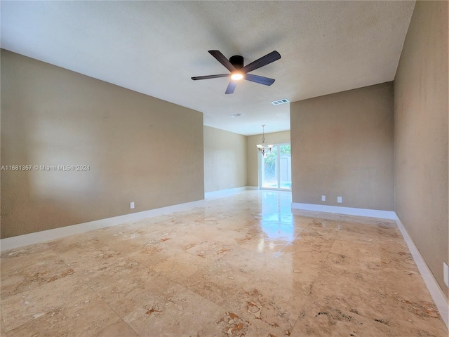 empty room with a textured ceiling and ceiling fan with notable chandelier