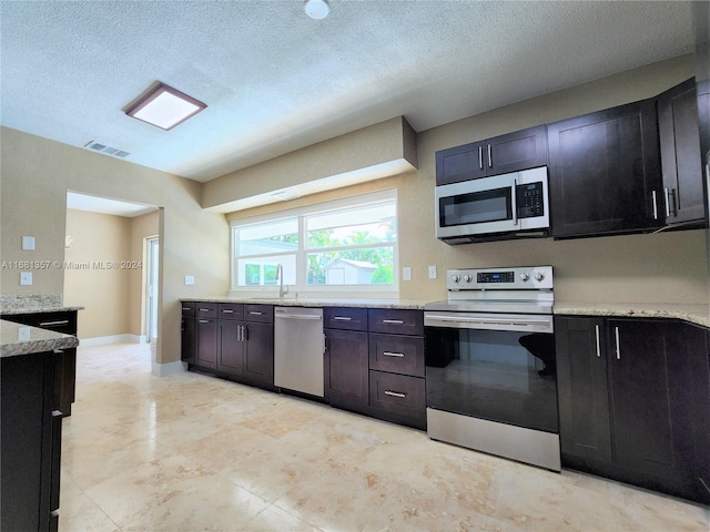 kitchen with light stone countertops, appliances with stainless steel finishes, and a textured ceiling