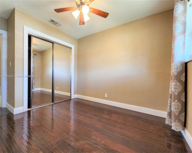 unfurnished bedroom featuring a closet, ceiling fan, and dark hardwood / wood-style flooring