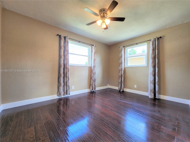 spare room featuring ceiling fan, a textured ceiling, a wealth of natural light, and dark hardwood / wood-style floors