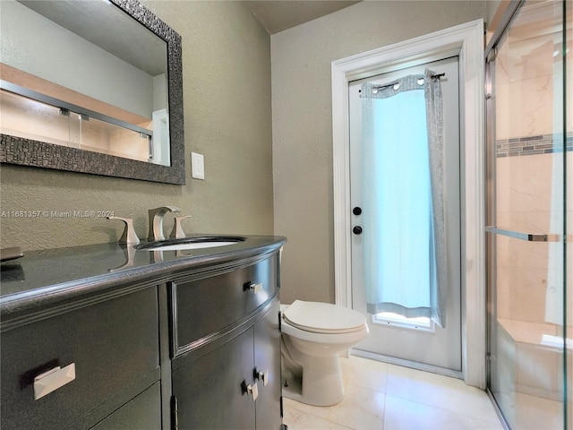 bathroom featuring vanity, a shower with shower door, toilet, and tile patterned floors