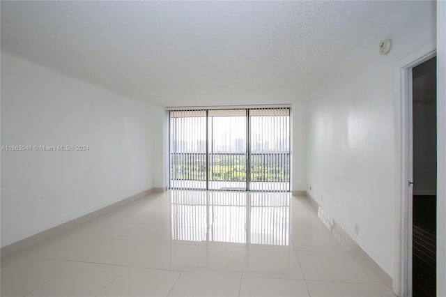 spare room with a textured ceiling, light tile patterned floors, and expansive windows