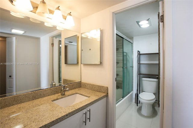 full bathroom with vanity, bath / shower combo with glass door, toilet, and tile patterned flooring