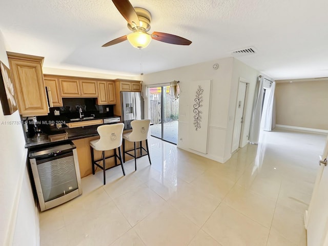 kitchen featuring a breakfast bar area, backsplash, sink, stainless steel fridge with ice dispenser, and ceiling fan