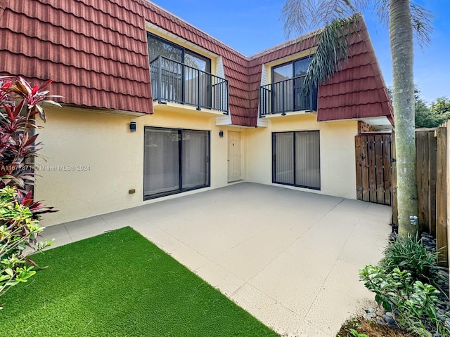 rear view of property featuring a patio area and a balcony