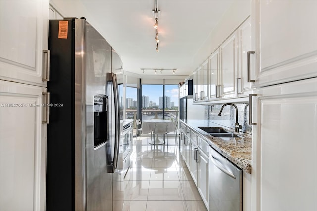 kitchen with light stone counters, appliances with stainless steel finishes, sink, and white cabinets