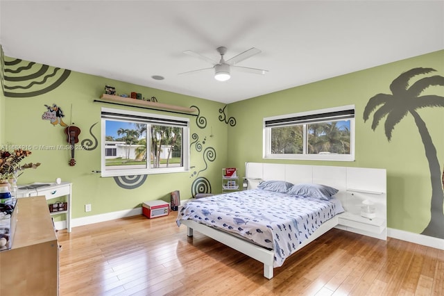 bedroom featuring ceiling fan, wood-type flooring, and multiple windows