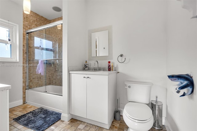 full bathroom featuring vanity, bath / shower combo with glass door, and toilet