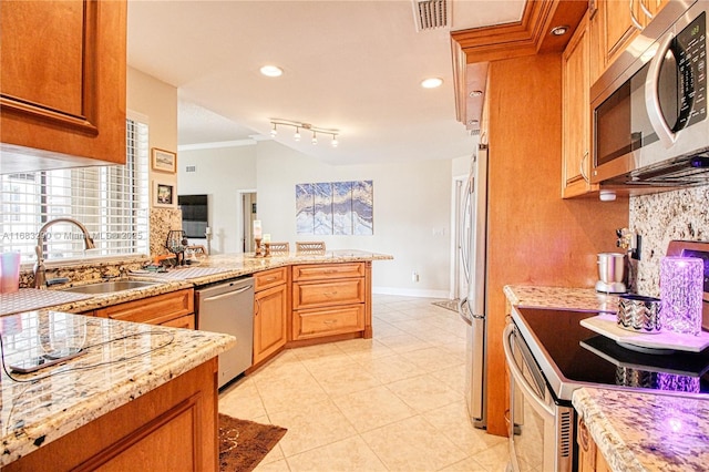 kitchen featuring stainless steel appliances, tasteful backsplash, sink, and kitchen peninsula