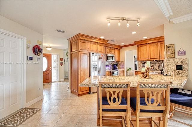 kitchen featuring appliances with stainless steel finishes, decorative backsplash, ornamental molding, light tile patterned floors, and kitchen peninsula