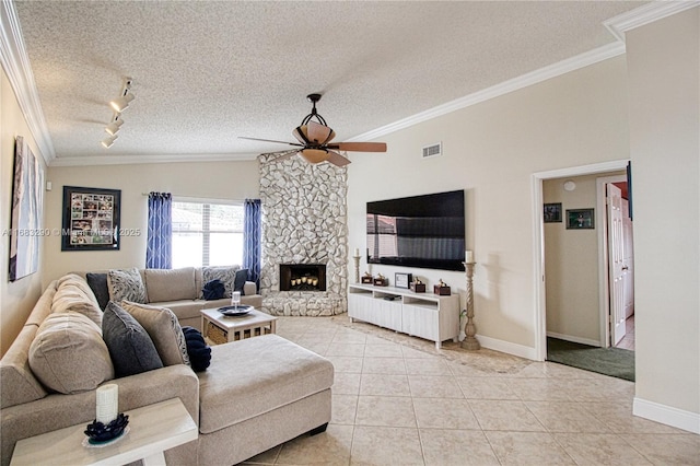 living room featuring a textured ceiling, light tile patterned floors, ornamental molding, ceiling fan, and a fireplace