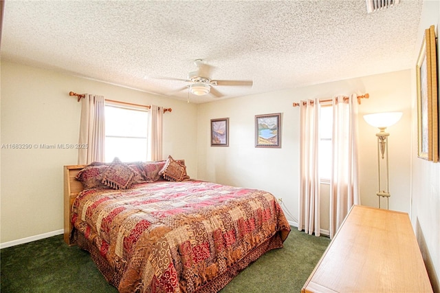 bedroom with a textured ceiling, ceiling fan, and dark colored carpet