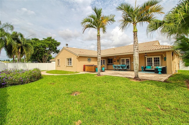 back of property with a patio, an outdoor living space, a yard, ceiling fan, and a hot tub