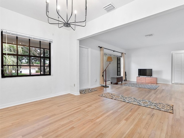 unfurnished living room with light hardwood / wood-style floors and an inviting chandelier