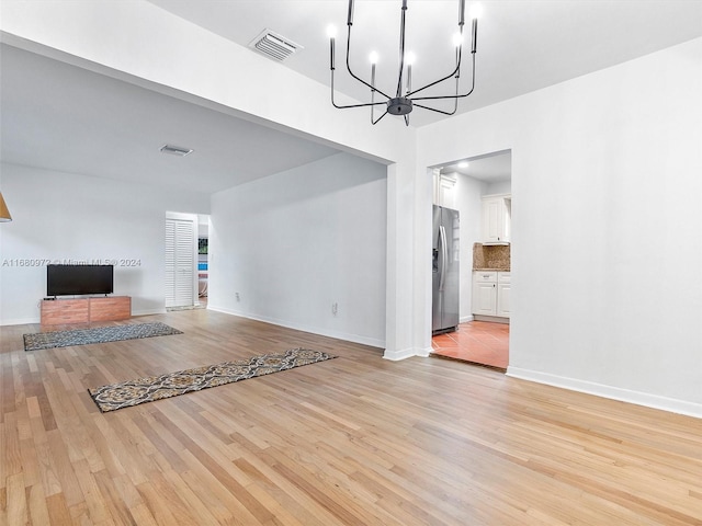 unfurnished living room featuring light hardwood / wood-style floors and a notable chandelier