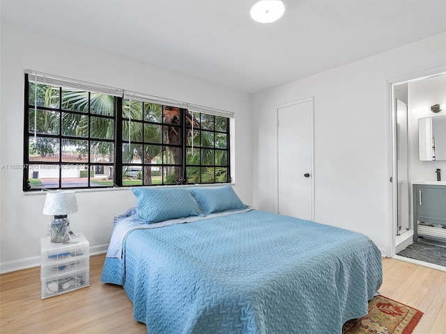 bedroom featuring light hardwood / wood-style flooring, multiple windows, and ensuite bath