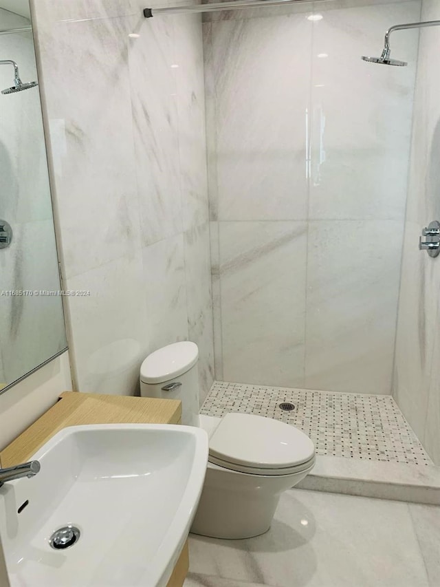 bathroom with sink, toilet, tile walls, tiled shower, and tile patterned flooring