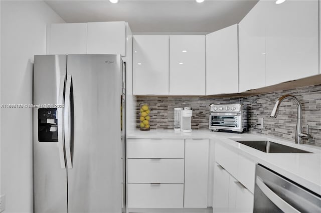 kitchen featuring backsplash, appliances with stainless steel finishes, sink, and white cabinets