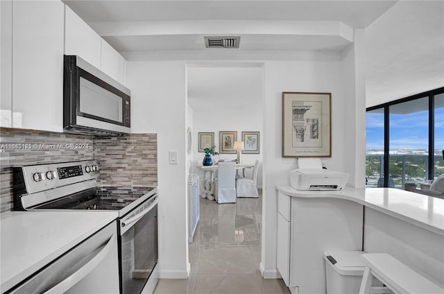 kitchen featuring white cabinetry, backsplash, appliances with stainless steel finishes, and light tile patterned flooring