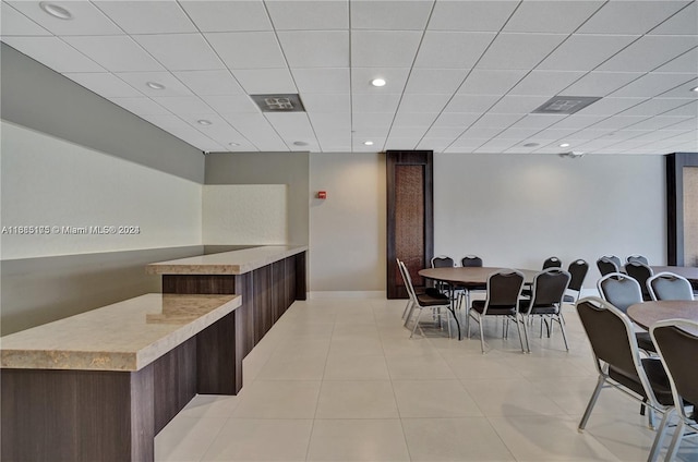 dining area with light tile patterned floors and a drop ceiling