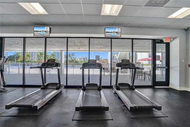 exercise room featuring a drop ceiling and a wall of windows