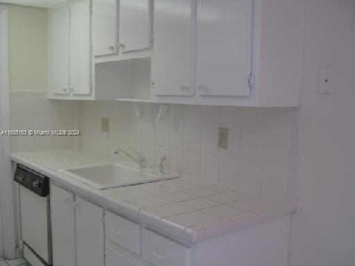 kitchen with sink, dishwasher, white cabinetry, and tasteful backsplash