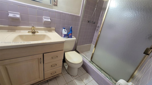 bathroom with vanity, tile patterned flooring, toilet, tile walls, and a shower with shower door