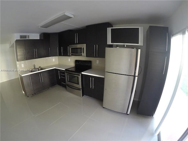 9367 Fontainebleau Blvd Unit G120, Miami, FL 33172 - kitchen featuring stainless steel appliances, dark cabinetry, light countertops, and light tile patterned flooring