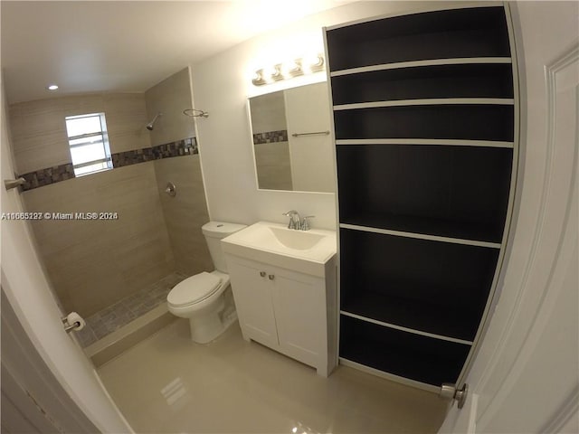 bathroom with toilet, vanity, and a tile shower