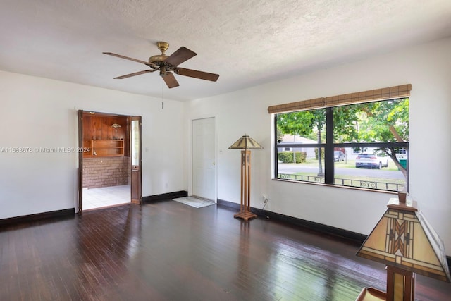 unfurnished room with ceiling fan, a textured ceiling, and dark hardwood / wood-style flooring