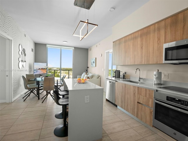 kitchen with stainless steel appliances, decorative light fixtures, sink, a kitchen breakfast bar, and a center island