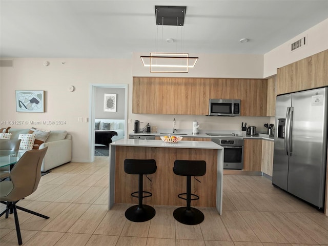 kitchen featuring appliances with stainless steel finishes, a breakfast bar area, sink, and a kitchen island