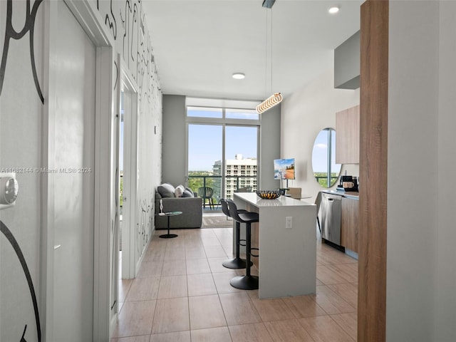 kitchen with kitchen peninsula, light tile patterned floors, a kitchen breakfast bar, stainless steel dishwasher, and decorative light fixtures