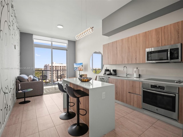 kitchen with stainless steel appliances, sink, a breakfast bar, light tile patterned floors, and a kitchen island