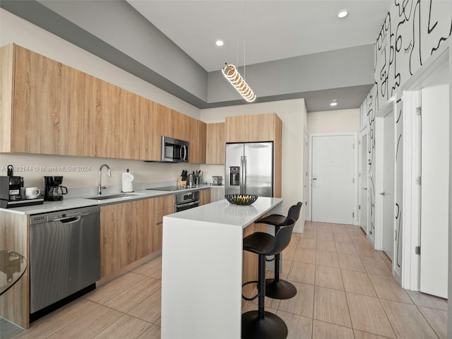 kitchen with a kitchen bar, stainless steel appliances, sink, and a kitchen island